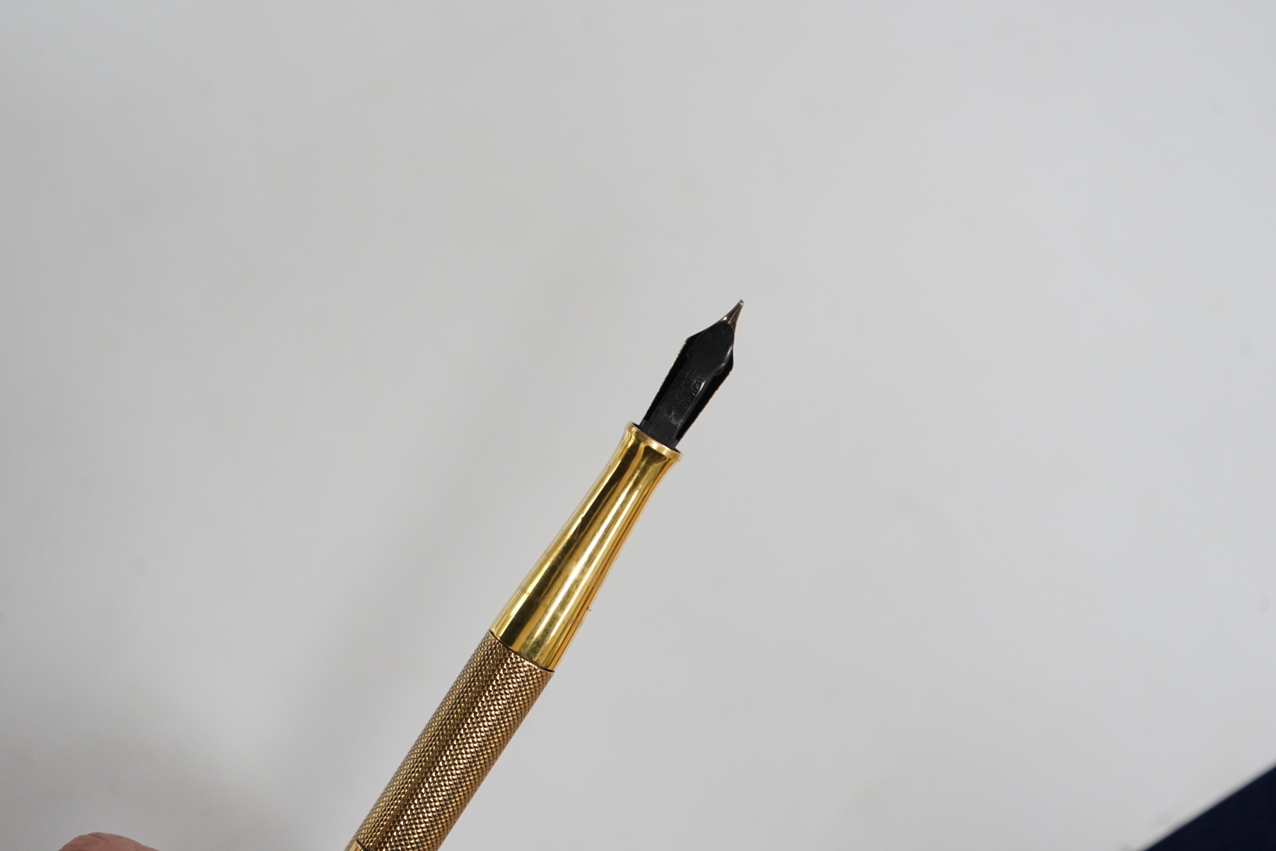 A George V engine turned 9ct. gold combination fountain pen and pencil, with holder (once attached to a stand), maker F.D.W. London, 1935, 20.4cm.